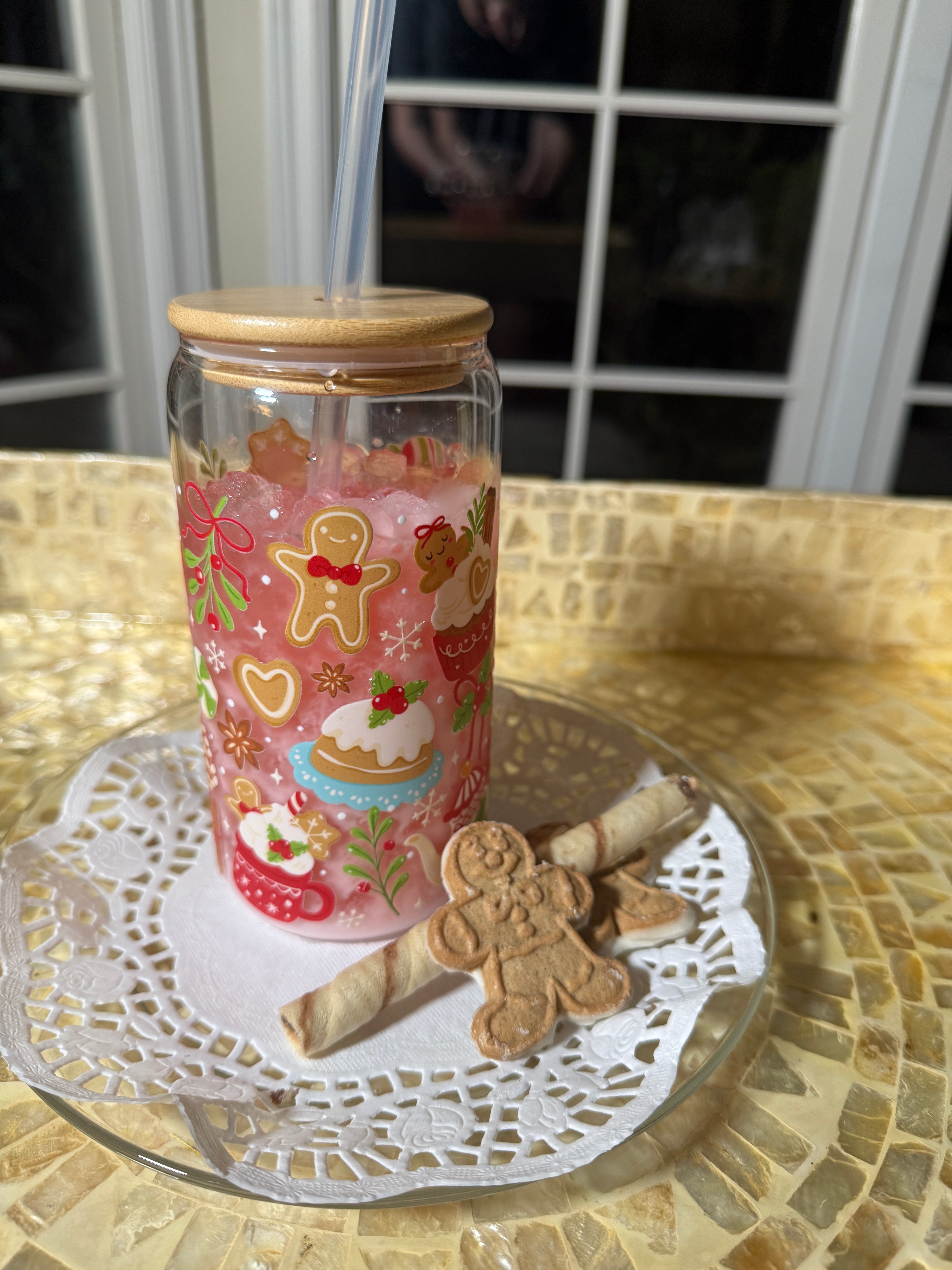 Decorative glass jar with gingerbread-themed paper and a small gingerbread man figurine on a lace doily.