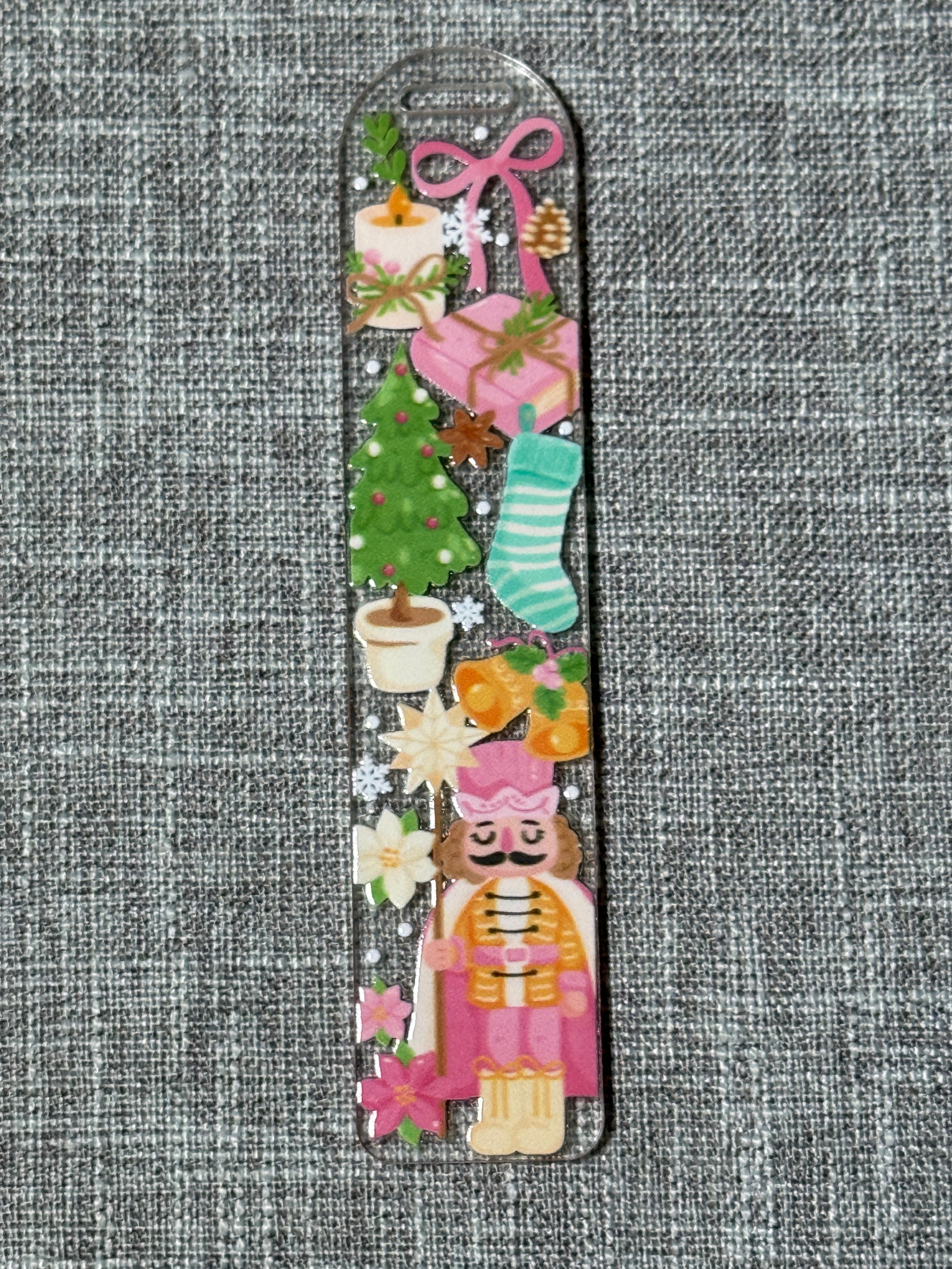 Close-up of Sugar Plum Nutcracker acrylic Christmas bookmark with tree, stocking, candle, and nutcracker in pink and gold.
